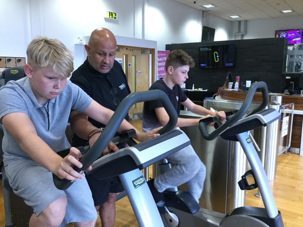 Newport Live instructor talking  to two young boys on fitness bikes