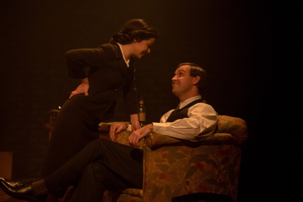 Promotion image for theatre show Nye & Jennie. Lady leans over man sitting in arm chair