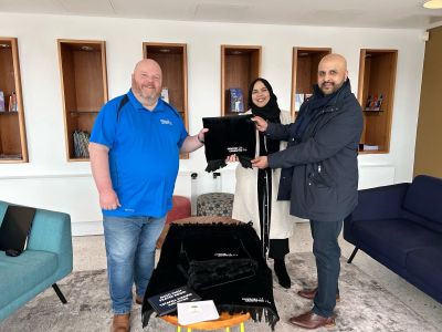 Kevin Ward, Rusna Begum and Sadique Maskeen holding prayer mat